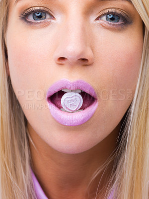 Buy stock photo Woman, closeup and studio portrait with candy in mouth for makeup, lipstick and heart sign for kiss. Girl, person and model for beauty with sweets, emoji and zoom of face for eating with cosmetics
