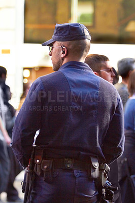 Buy stock photo Rearview shot of a policeman doing crowd control