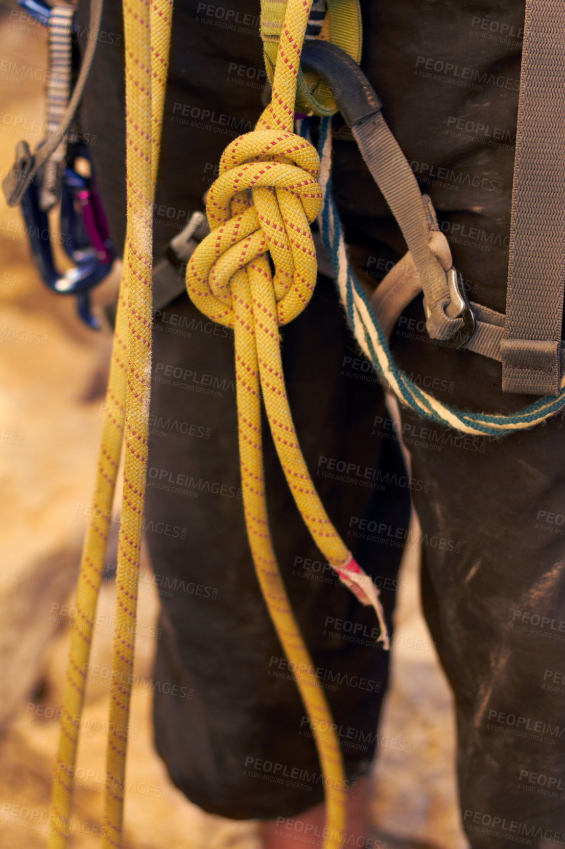 Buy stock photo Cropped shot of a young rock climber standing and adjusting his harnesses