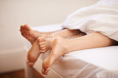 Buy stock photo Cropped view of a couple's feet as they lie in bed together