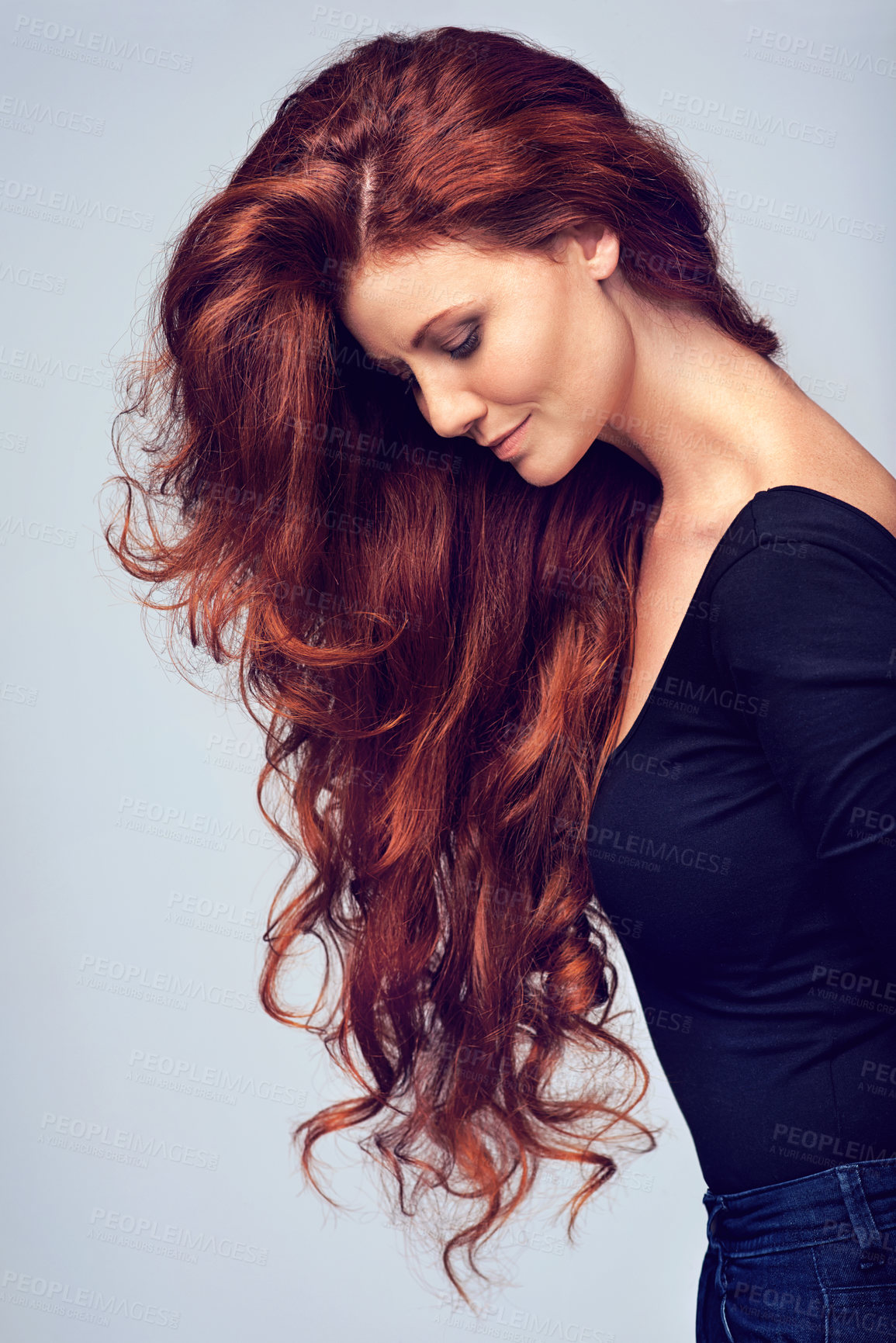 Buy stock photo Studio shot of a young woman with beautiful red hair posing against a gray background