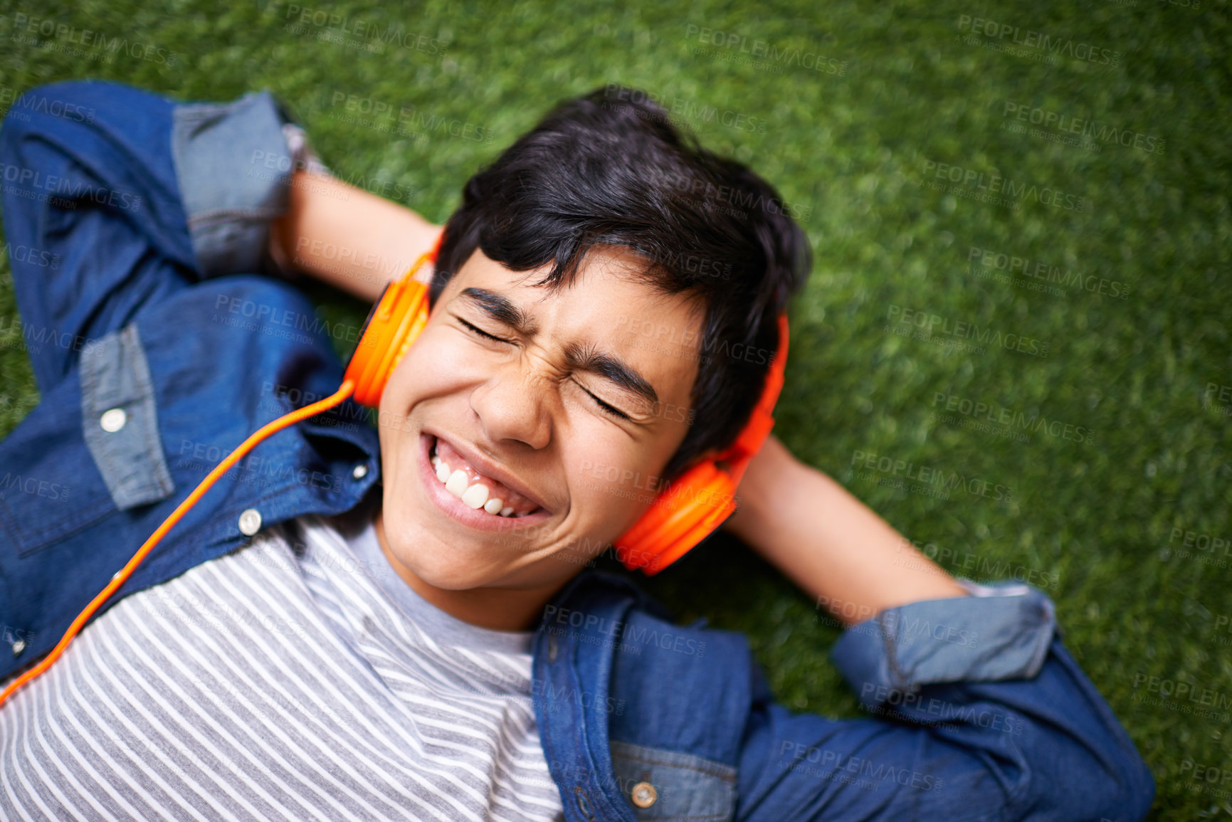 Buy stock photo Boy child, lawn and lying with headphones, free or excited for music, streaming or online audio in top view. Male kid, happiness and listen to sound, internet radio or podcast on grass in garden