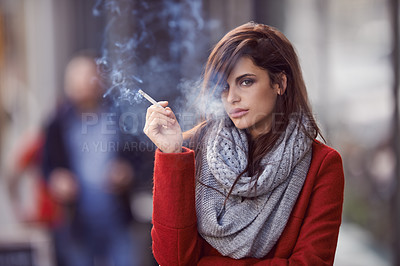 Buy stock photo Portrait of a beautiful and fashionable young woman smoking a cigarette in an urban setting
