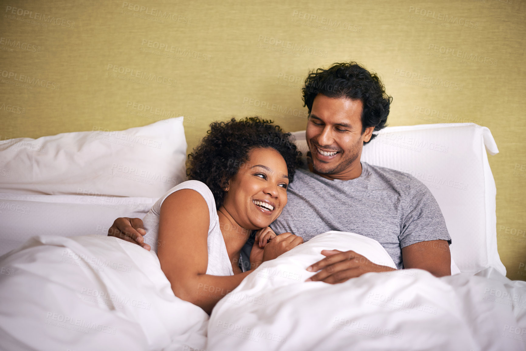 Buy stock photo A young husband and wife lying bed together