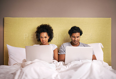 Buy stock photo A young couple in bed with their laptops