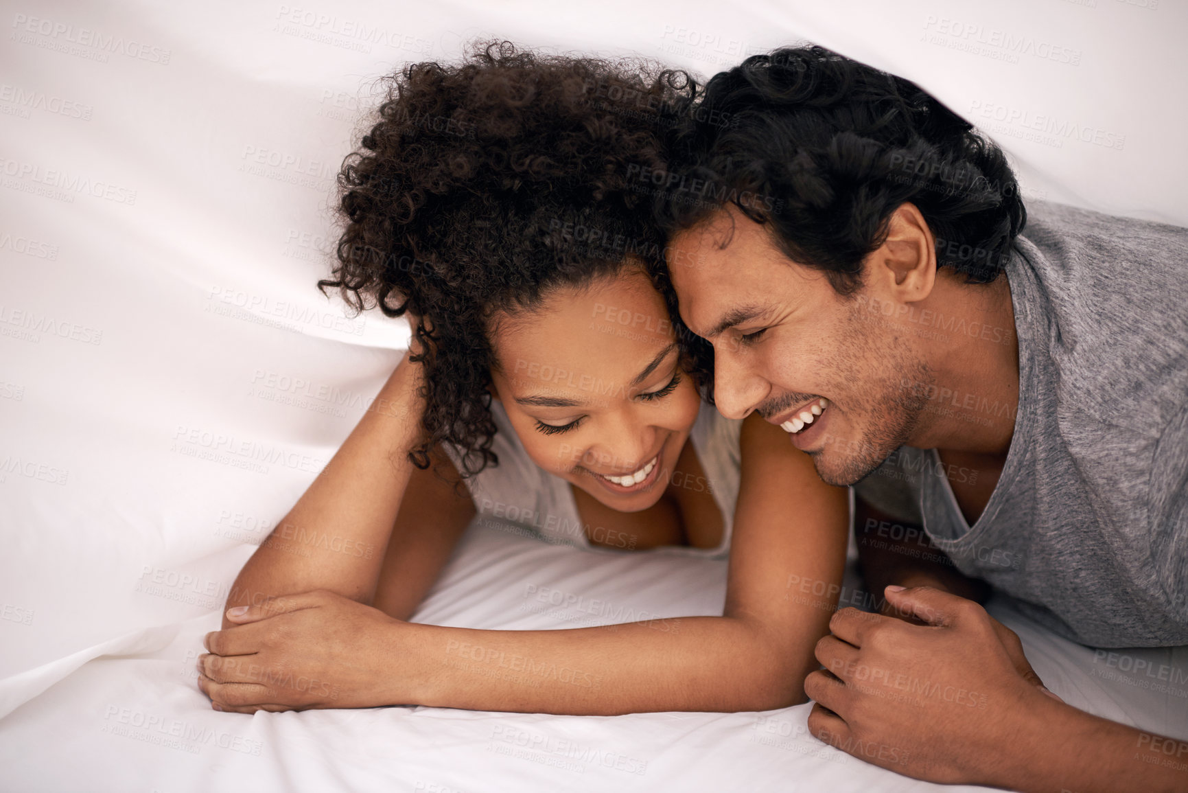 Buy stock photo Couple, bed and sheet for relax morning with resting smile for partnership, bonding or apartment. Man, woman and happiness under linen for honeymoon laughter for vacation getaway, carefree or playful