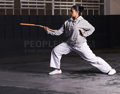 Buy stock photo Martial arts, woman and fitness with weapon for training with nunchaku, exercise and practice for self defence at night. Karate, athlete and workout for fighting, discipline or technique in warehouse
