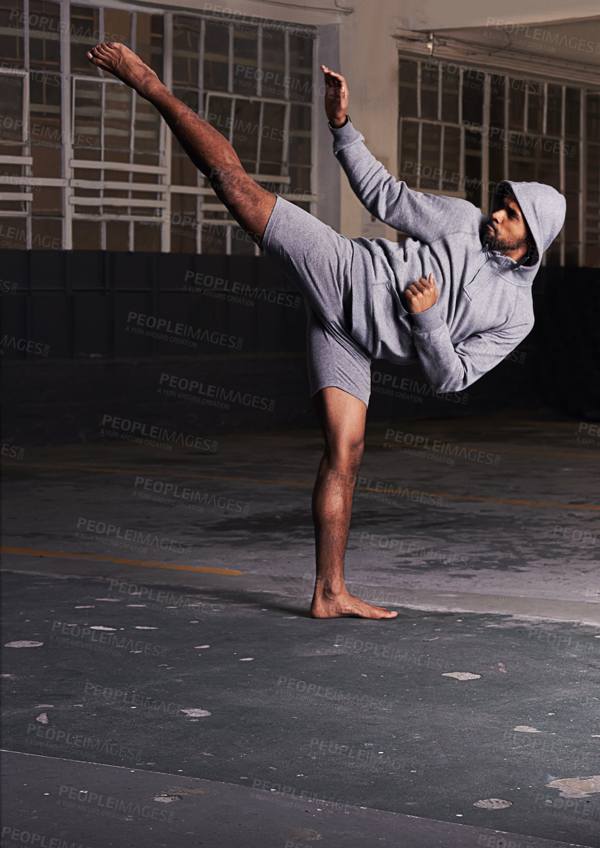 Buy stock photo Shot of a barefoot young man in activewear doing martial arts in a parking lot