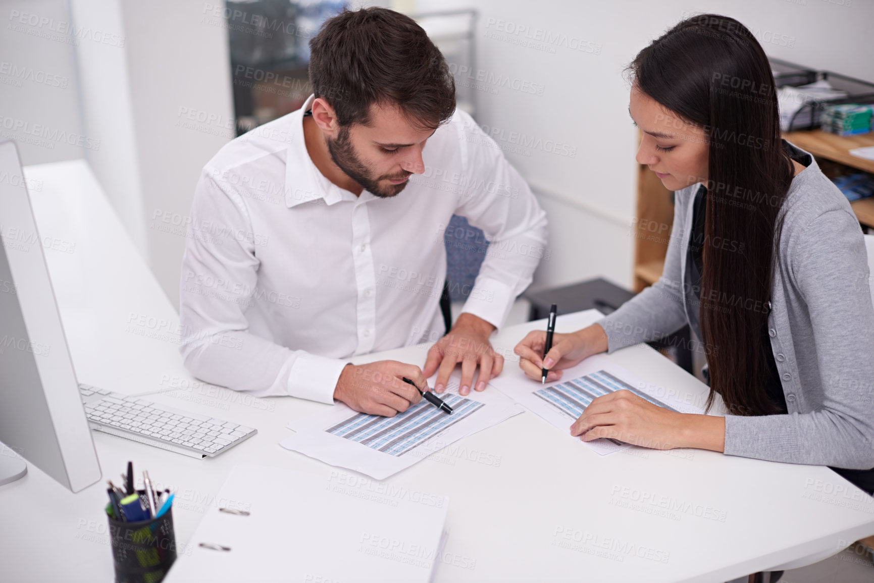 Buy stock photo Shot of two young business colleagues discussing documents in the office