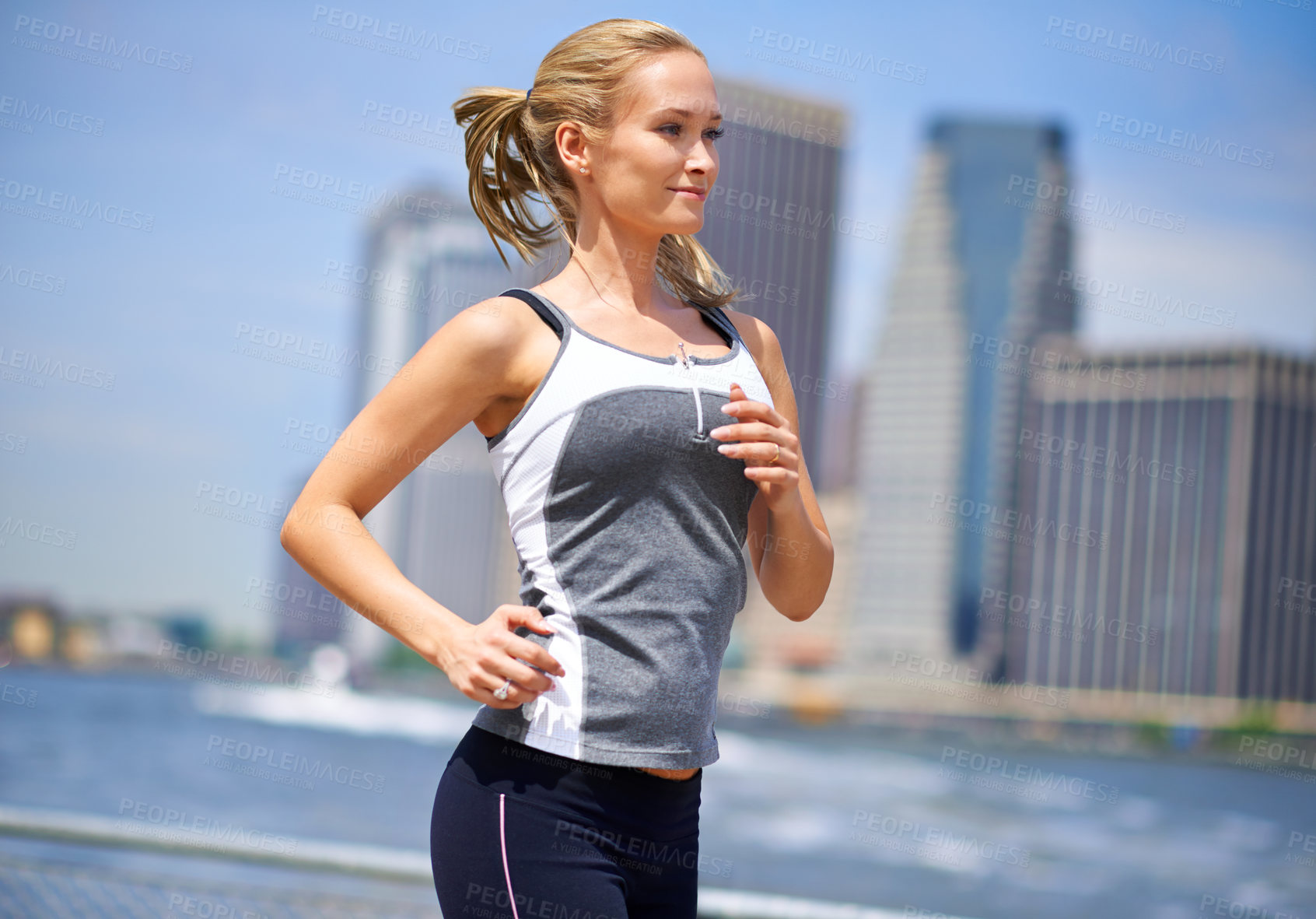 Buy stock photo Shot of an attractive blonde woman jogging in an urban setting