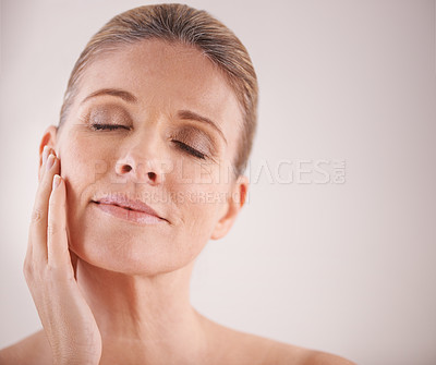 Buy stock photo Face, beauty and mockup with a mature woman in studio on a mockup background for natural antiaging treatment. Facial, skincare and wellness with an attractive elderly female model touching her cheek