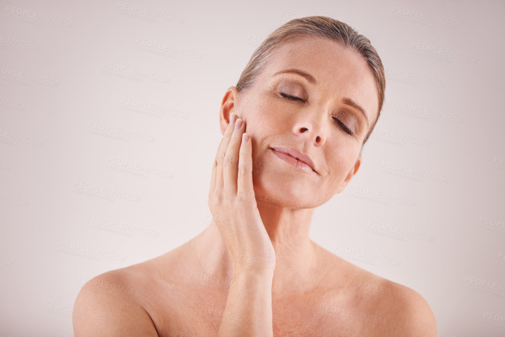 Buy stock photo Cropped studio shot of a beautiful mature woman touching her face