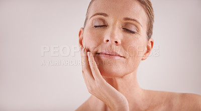 Buy stock photo Face, beauty and mockup with a mature woman in studio on a gray background for natural antiaging treatment. Facial, skincare and wellness with an attractive senior female model touching her cheek