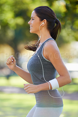 Buy stock photo Sports, earphones and athlete running in a park for health, wellness and outdoor exercise. Nature, fitness and female runner doing cardio workout in garden listening to music or radio and training.