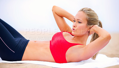 Buy stock photo Shot of a young woman in sportswear doing situps on the beach