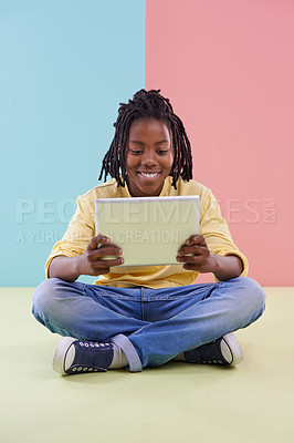 Buy stock photo Teenager, reading and tablet in studio for online education, e learning and creative games on floor. Kid, student or african boy with digital technology in pastel color or blue and pink background