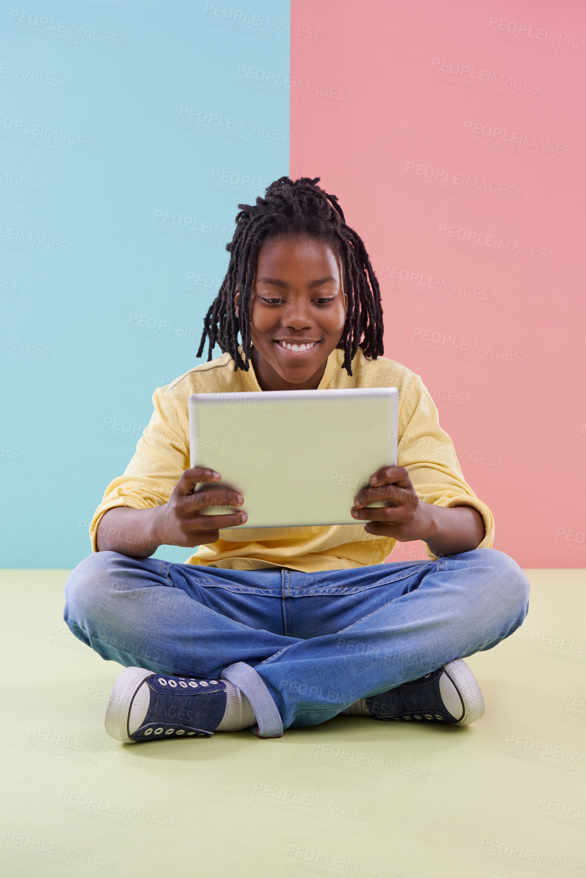 Buy stock photo Teenager, reading and tablet in studio for online education, e learning and creative games on floor. Kid, student or african boy with digital technology in pastel color or blue and pink background