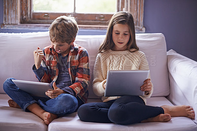 Buy stock photo Shot of a young brother and sister playing on their digital tablets