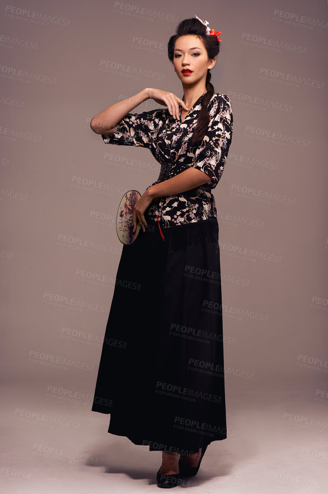Buy stock photo Fashion, fan and Japanese woman with geisha confidence and Asian clothing with traditional outfit in studio. Culture, creative and ancient art and clothes with person from Japan with brown background