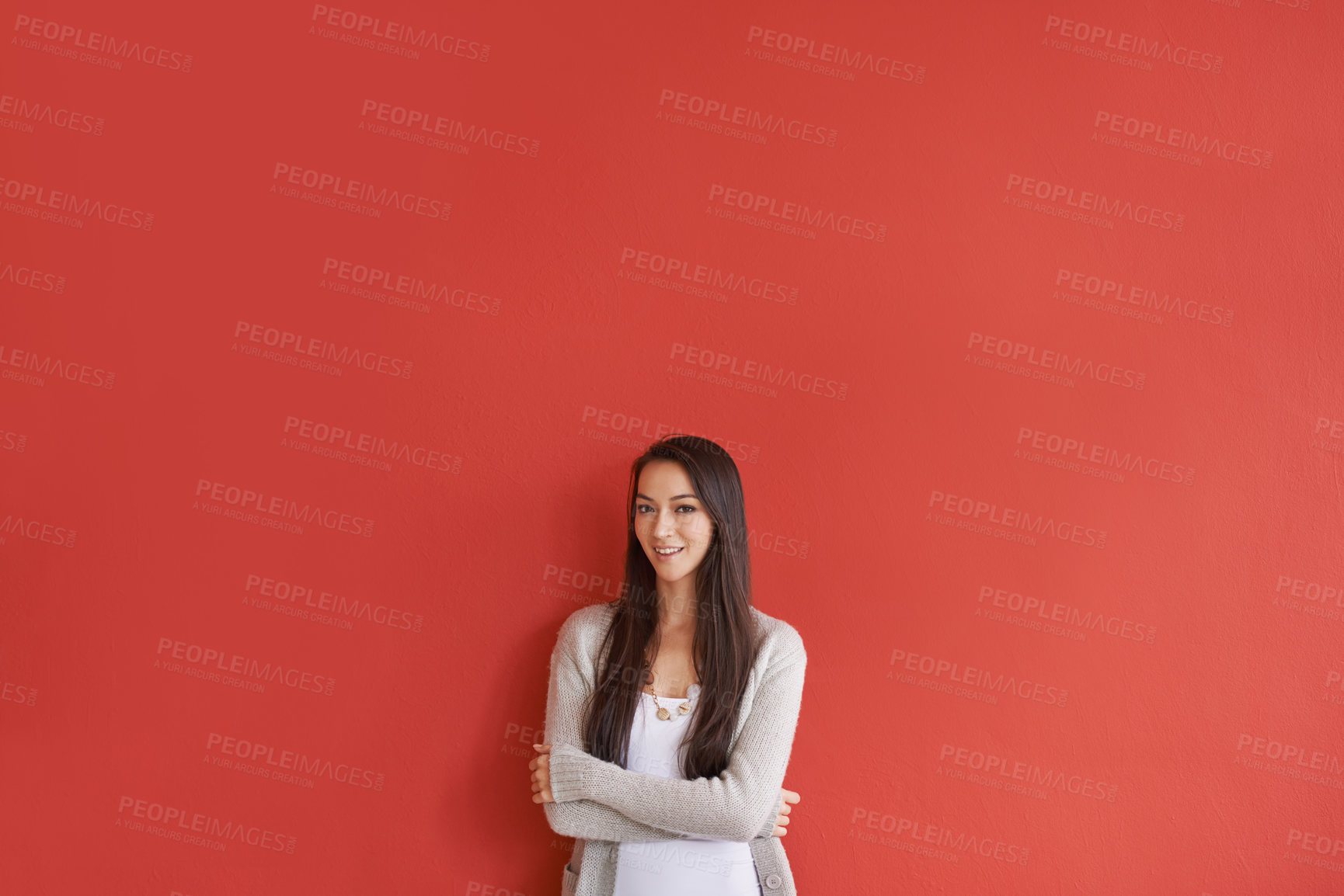 Buy stock photo Portrait of an attractive young woman standing against a red background