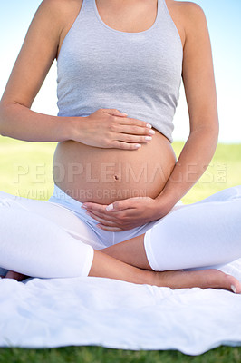 Buy stock photo Cropped shot of a pregnant woman doing yoga outdoors
