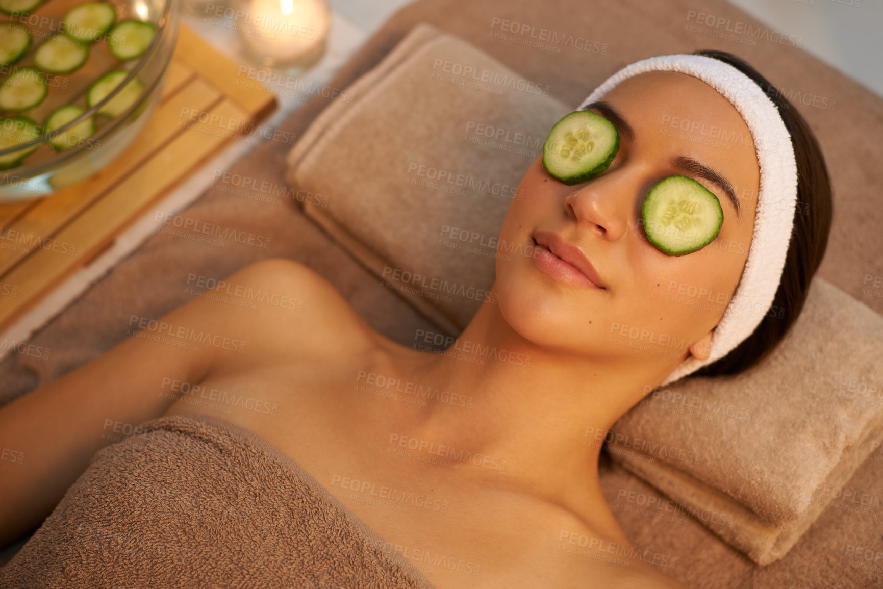 Buy stock photo Top view, skincare and woman with cucumber on eyes at massage table in spa for peace, relax or wellness. Mask, above and person with vegetable on face for natural beauty or healthy organic treatment