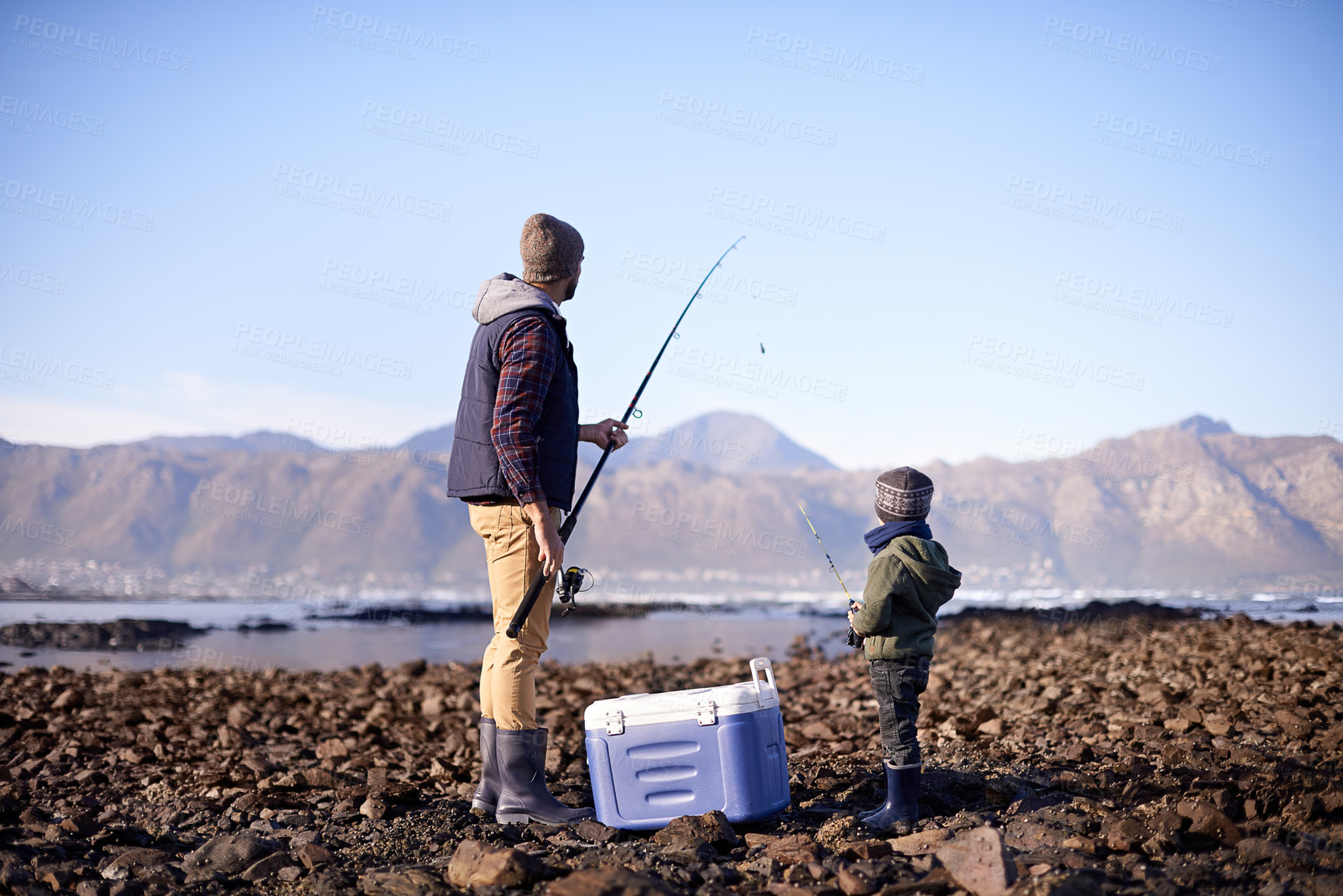 Buy stock photo Shot of a father and son standing with their fishing gear by the sea