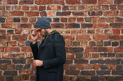 Buy stock photo Fashion, man and thinking on brick wall with glasses for trendy, cool and style for urban with idea. Male person, outdoor and planning for weekend or holiday with winter outfit and stylish in Germany