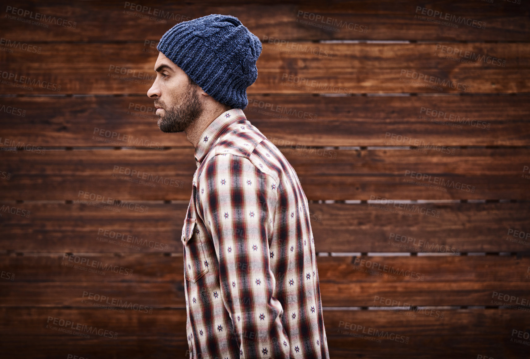 Buy stock photo Shot of a handsome young man in trendy winter attire against a wooden background