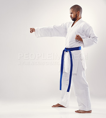 Buy stock photo Studio, karate and African man training technique for physical health of blue belt instructor. White background, male person and adult with disciple of martial arts, sport and fist for combat