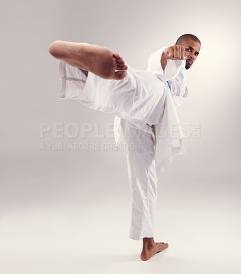 Buy stock photo Karate, exercise and man kick in portrait on studio, white background or mockup of martial arts. Serious, warrior and training to fight with foot and punch fist with power in competition for sport
