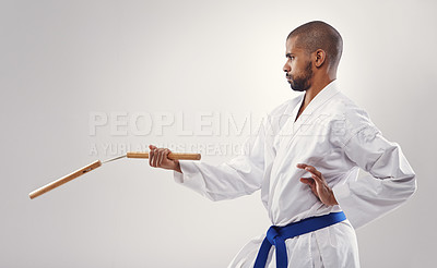 Buy stock photo Nunchucks, karate and man in martial arts fight with weapon in training for defence in white background of studio. Nunchaku, exercise and fighting with equipment in sport with skill and power in club