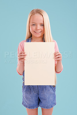 Buy stock photo Child, portrait and poster mockup in studio for presentation for good news placard on blue background, announcement or board. Female person, face and smile or information banner, contact us or paper