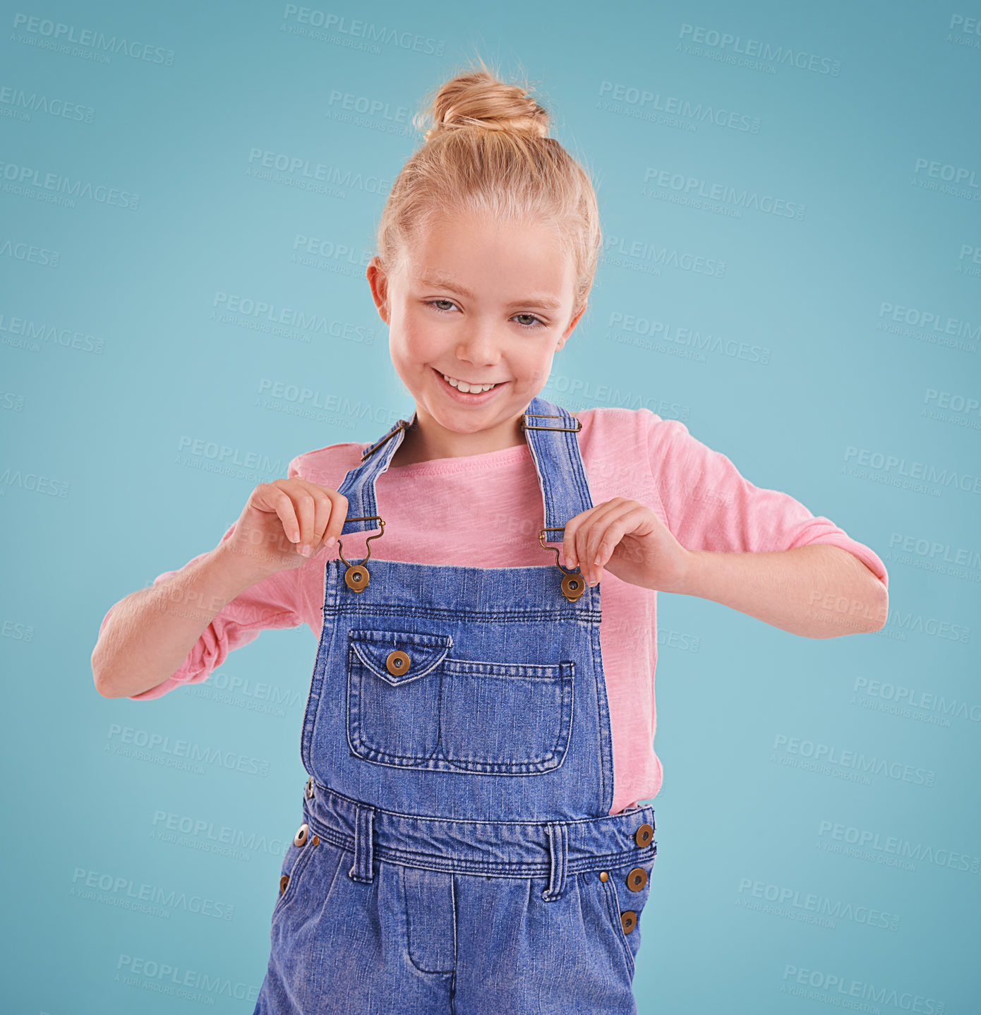 Buy stock photo Child, portrait and smile in studio with confidence in dungarees on blue background, fashion or mockup space. Girl, school student and positive childhood in Australia with good mood, growth or kid