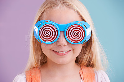 Buy stock photo Child, background and colour with fashion glasses, happy smile on girl with hypnotic eyewear in studio. Groovy, funky and playful hipster style, trendy kid with cool vibrant pattern for accessories