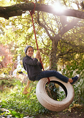 Buy stock photo Boy, child and tyre swing with portrait in garden with smile, playing and countryside vacation in summer. Kid, face and diy adventure playground in backyard of home with sunlight and trees in nature