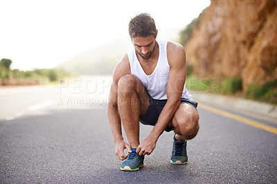Buy stock photo Man, runner and tying laces on road for workout, prepare and sneakers for cardio or training for marathon. Male person, feet and fitness on mountain for performance, athlete and ready for exercise