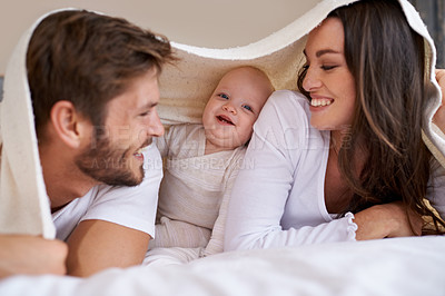Buy stock photo Happy mother, father and baby with blanket on bed for love, care and quality time together. Parents, family and playful newborn child relaxing in bedroom with bedding fort, smile and bonding at home