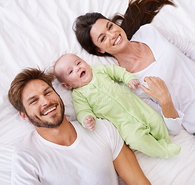 Buy stock photo Above, portrait and happy parents with baby on bed for love, care and quality time together at home. Smile of mother, father and family with cute newborn kid relax in bedroom, support and happiness