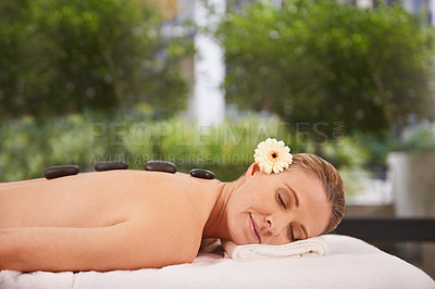 Buy stock photo Woman, hands and hot stone massage at spa with eyes closed, flower for natural treatment and wellness with zen. Calm, peace and luxury with warm rocks for detox, self care and holistic healing