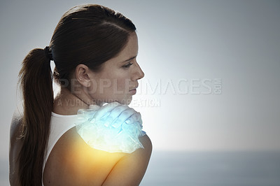 Buy stock photo Shot of a young woman holding an icepack on her shoulder to ease the pain