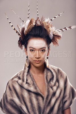 Buy stock photo Woman, portrait and art with fashion of Native American in traditional clothing on a gray studio background. Female person with feather, face paint or stylish tribal outfit of goddess in beauty