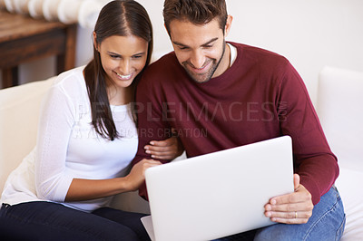 Buy stock photo An affectionate young couple using their laptop together at home