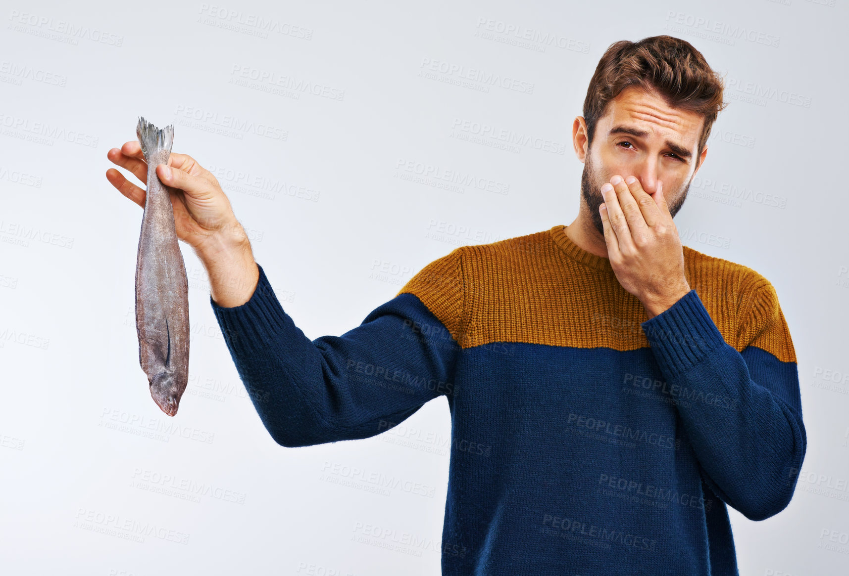 Buy stock photo Man, disgust and fish with smelling odor, bad stench of animal or sea creature on a gray studio background. Male person with gross facial expression of disgusted aroma or smelly odd stink on mockup