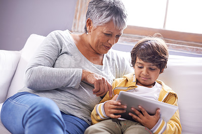 Buy stock photo Shot of a grandmother and grandson sitting at home using a digital tablet together