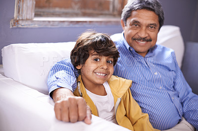 Buy stock photo Portrait of a smiling grandfather and grandson sitting on a sofa at home
