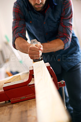 Buy stock photo Shot of a handsome young carpenter measuring a piece of wood