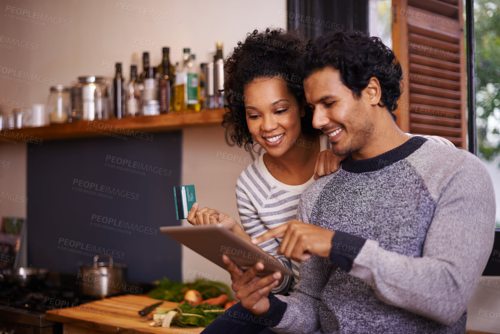 Buy stock photo Shot of a young couple using their tablet together while they get ready to prepare a meal