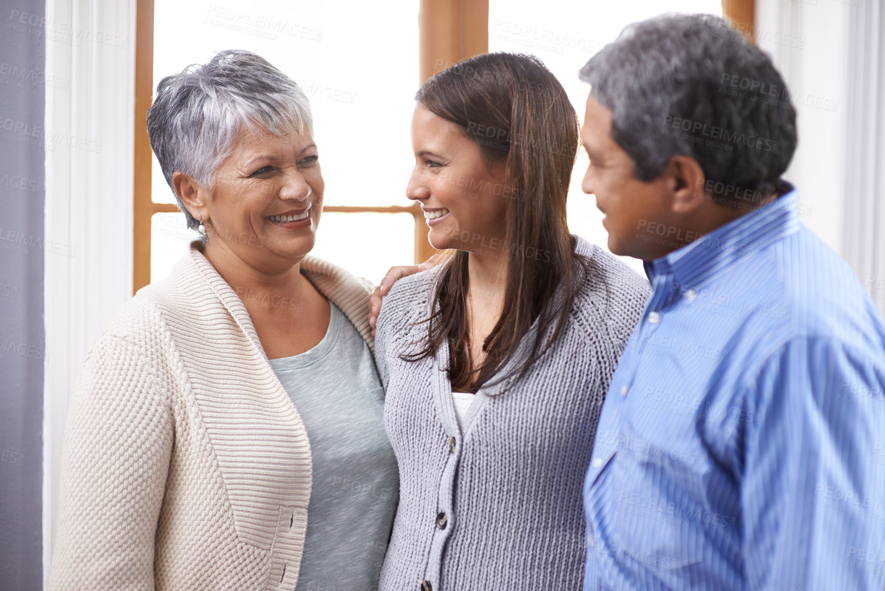 Buy stock photo Shot of a senior couple standing with their adult daughter at home