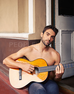 Buy stock photo Cropped shot of a shirtless young man playing guitar at home